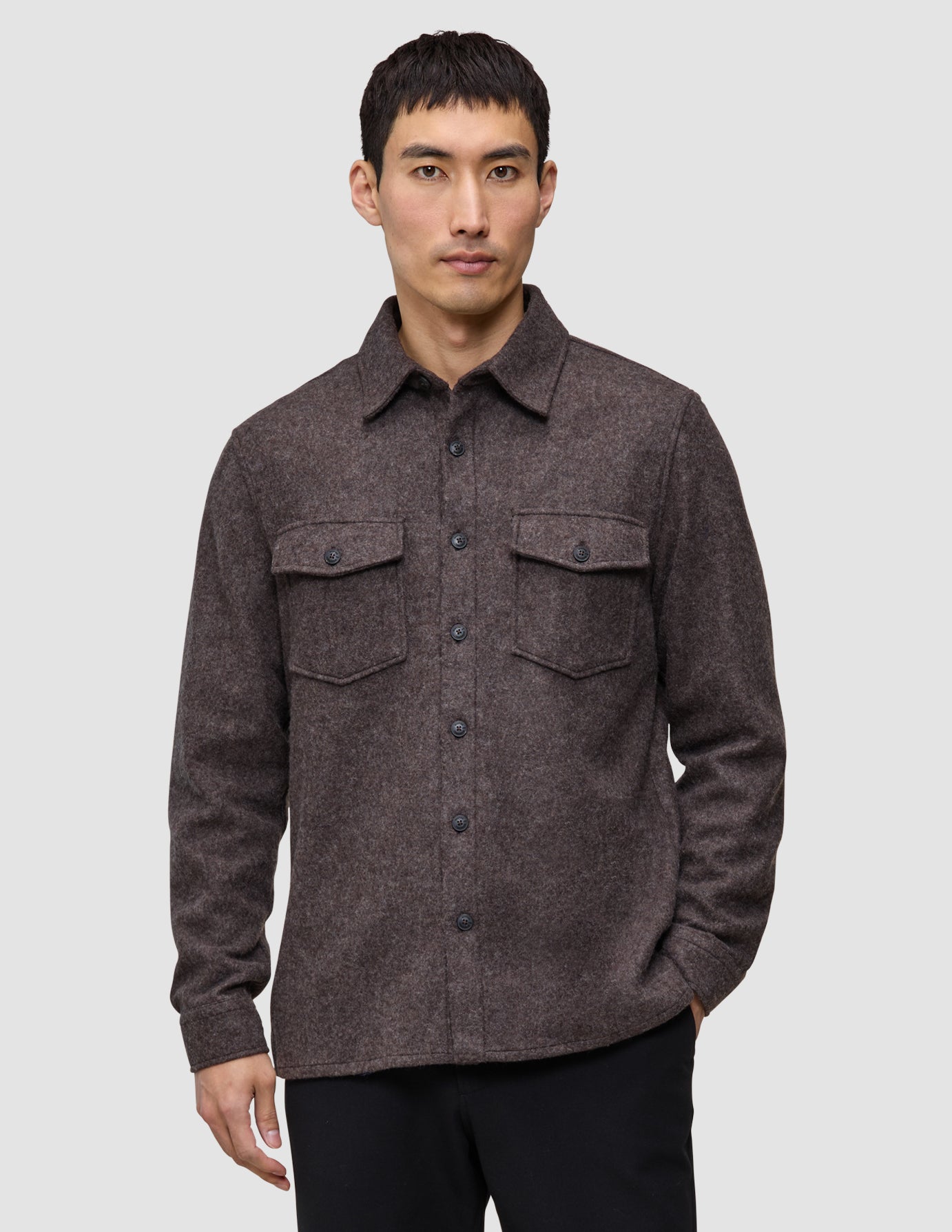 A man wearing a Double Layer Wool Overshirt in saddle brown, featuring a button-up front and two chest pockets.